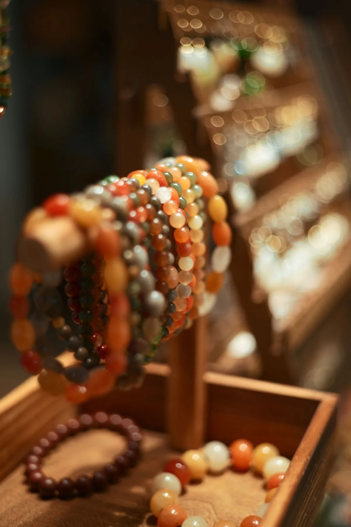 Warm agate and gemstone beaded bracelets displayed on a wooden stand
