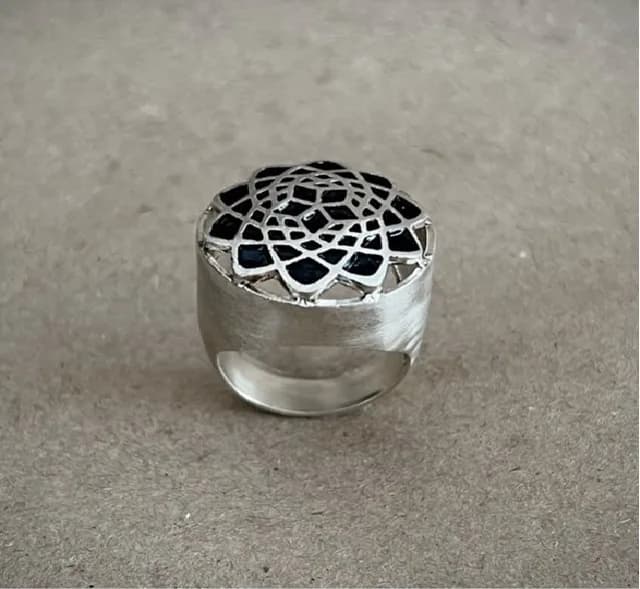 Silver statement ring with a black onyx lattice face on a neutral surface