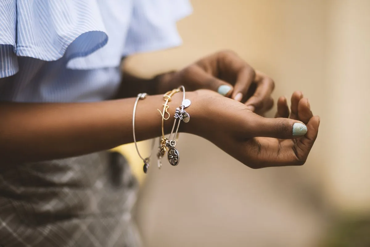Stacked gold and silver charm bracelets on the wrist