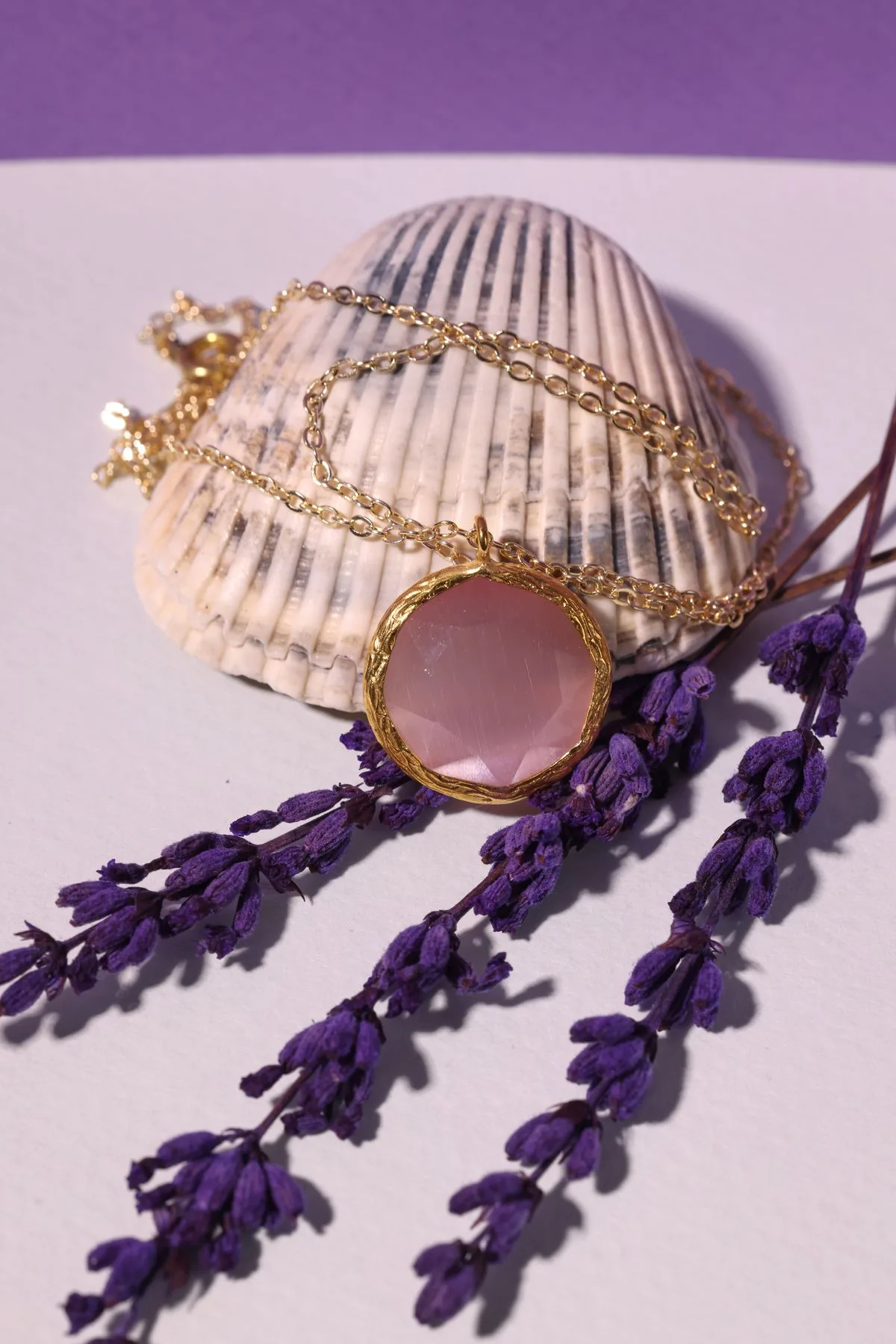 Gold-plated Solara pendant with a faceted rose quartz stone on a seashell